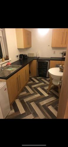 a kitchen with wooden cabinets and a geometric floor at Lovely ground floor apartment with easy parking. in Belfast