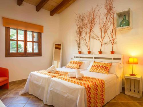 Schlafzimmer mit einem großen Bett mit orangefarbener und weißer Bettwäsche in der Unterkunft Can Suau in Llubí