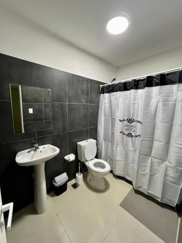 a bathroom with a toilet and a sink and a shower curtain at Black Star Art Hostel in Neuquén