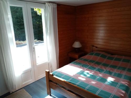 a bedroom with a bed and a sliding glass door at Chambre calme en correze in Sainte-Fortunade