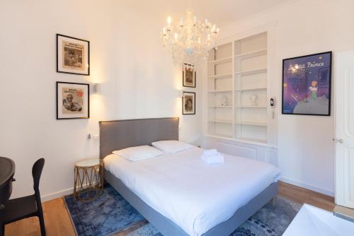 - une chambre avec un lit blanc et un lustre dans l'établissement Le précieux de Nicolas, à Nancy