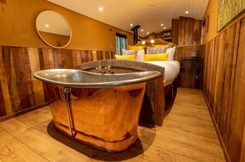 a bathroom with a large wooden tub next to a bed at Ashwood Shepherd Hut -Ockeridge Rural Retreats in Worcester