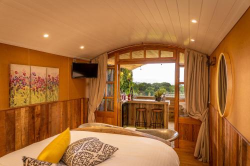 Ashwood Shepherd Hut -Ockeridge Rural Retreats في وستر: غرفة نوم مع سرير وإطلالة على بار