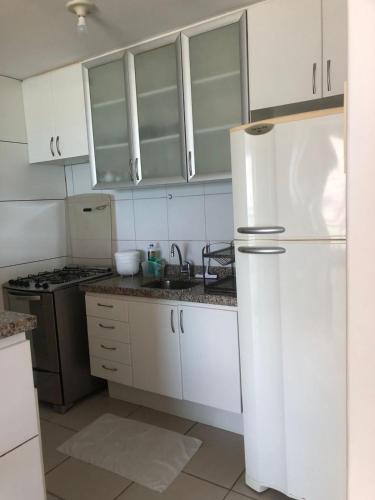a kitchen with white cabinets and a white refrigerator at APARTAMENT BEACH FORTALEZA in Fortaleza