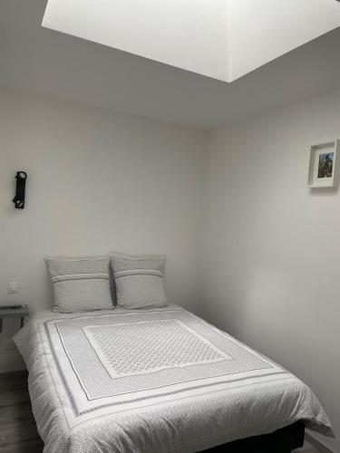 Dormitorio blanco con cama con sábanas y almohadas blancas en Gîte Le petit quartier, en Berson