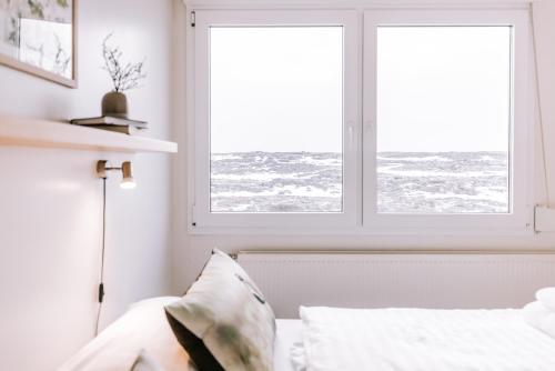 a bedroom with a bed and two windows at Hlid Bed and Breakfast in Myvatn