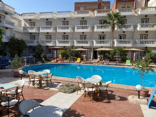 a hotel with a pool and tables and chairs at Zak Inn in Hurghada