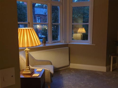 a living room with a lamp and a chair and windows at Victoria Lodge Woodhall Spa in Woodhall Spa