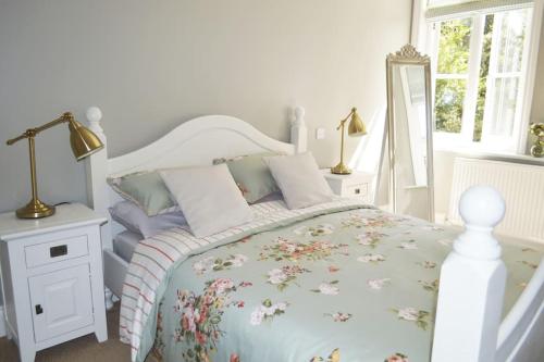 a bedroom with a white bed with a floral bedspread at Victoria Lodge Woodhall Spa in Woodhall Spa