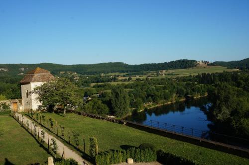- une vue sur une rivière avec un bâtiment et un vignoble dans l'établissement Maison d'amis, à Beynac-et-Cazenac