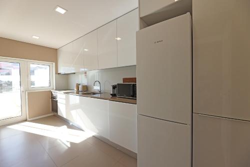 a kitchen with white cabinets and a refrigerator at Music Apartment I in Porto