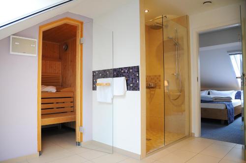 a bathroom with a shower and a bedroom at Hotelanlage Starick in Lübbenau
