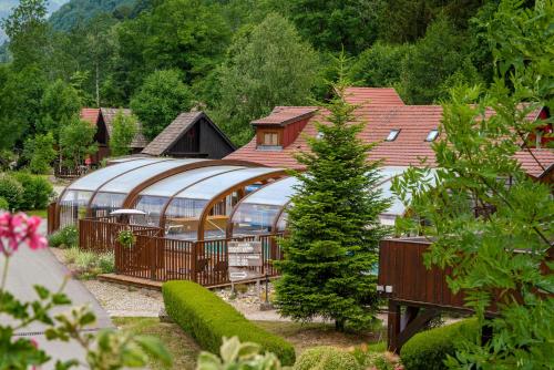 a large glass greenhouse in a garden with a tree at Chalets de la Wormsa in Metzeral