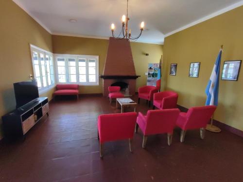 a living room with red chairs and a fireplace at Hostería de Ancasti in Ancasti