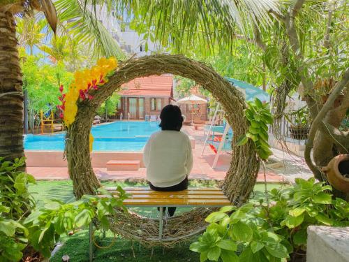 a woman sitting on a bench looking at a pool at MAY Bungalow in Mui Ne