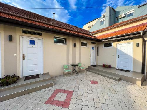 a patio with two white doors and a table and chairs at Dis apartman 2 in Kruševac