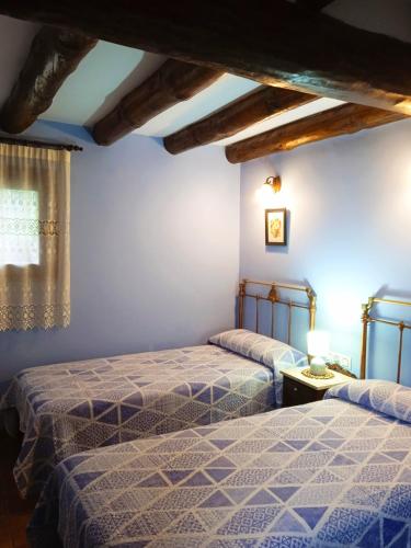 two beds in a room with blue walls at Casa La Tornagua in Biescas
