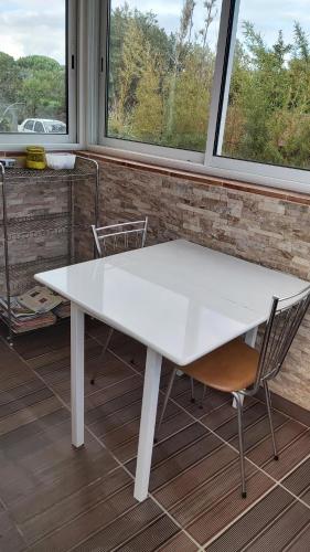 una mesa blanca y 2 sillas en una habitación con ventanas en Maison MICDEN, en Saint-Jean-Pla-de-Corts