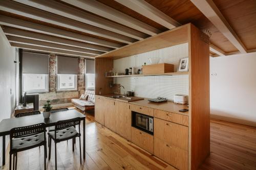 ポルトにあるStep In Porto Apartmentsのキッチン(木製キャビネット、テーブル、椅子付)
