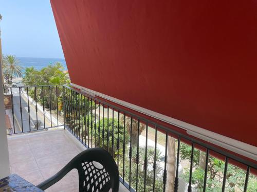 a black chair sitting on a balcony overlooking the ocean at El SOL del SUR in La Herradura