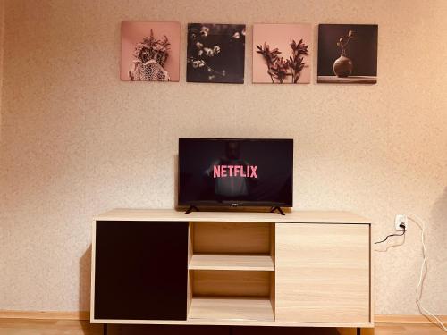 a television sitting on top of a wooden cabinet at Apartamenty KTW Park Śląski Luksusowy PRL in Katowice