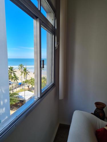 a bedroom with a window with a view of the beach at Apartamento Das Conchas Praia das Pitangueiras in Guarujá