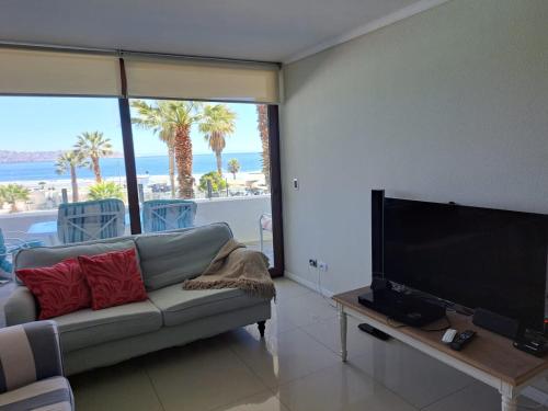 uma sala de estar com um sofá e uma televisão de ecrã plano em Condominio Jardín del Mar em Coquimbo