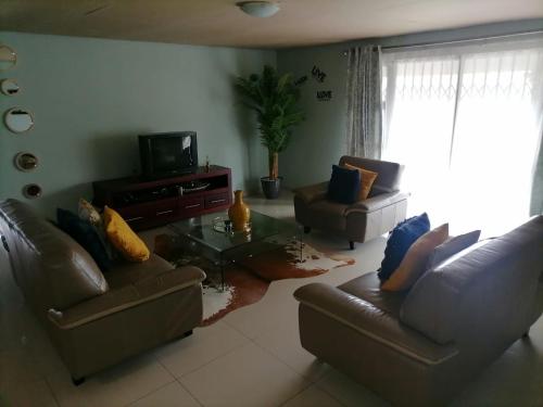 uma sala de estar com dois sofás e uma televisão em Queens And Kings Lodge em Durban