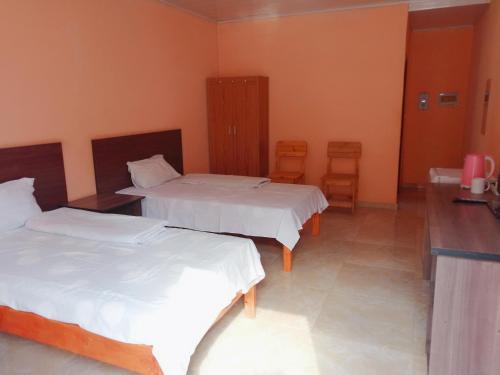 a hotel room with two beds and two chairs at Prosperous Guest House in Opuwo
