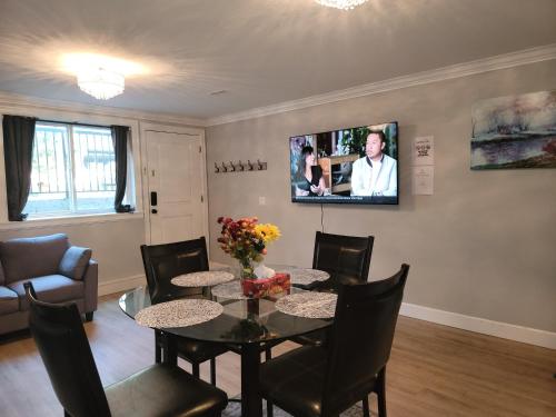 a dining room with a table and a tv on the wall at Oscar INN & 2bd Family Suite or Private Room in Abbotsford