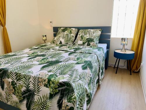 a bedroom with a bed with a green and white comforter at Square Village in Capesterre-Belle-Eau