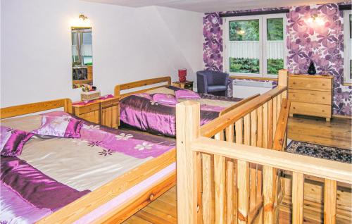 ビスクピエツにあるBeautiful Home In Biskupiec With Kitchenetteのベッドルーム1室(ベッド2台、木製ベビーベッド1台付)