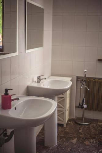a white bathroom with two sinks and a shower at 4 Couples & 4 Friends Hostel in Krakow