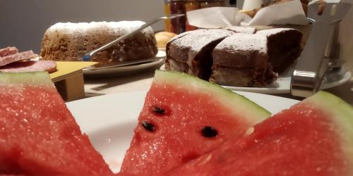 a slice of watermelon on a plate with a piece of cake at B&B Dimora Damiani in Montefiore dellʼAso