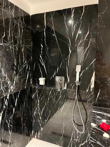 a bathroom with a shower with a black marble wall at Dar Andamaure in Marrakech