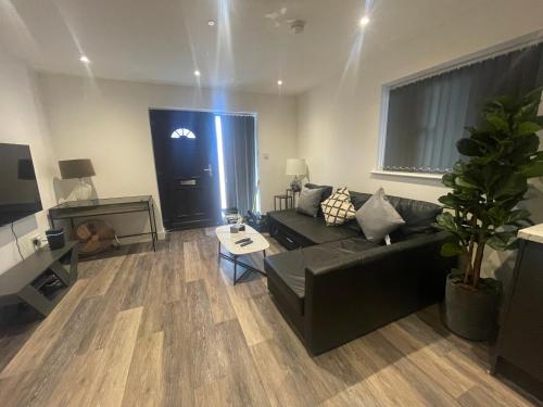 a living room with a black couch and a table at Sapphire Premier Apartments w/Secure Parking in Cardiff