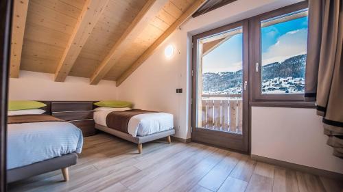 two beds in a room with a large window at Chalet 4 Stagioni in Livigno