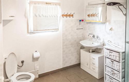 Baño blanco con aseo y lavamanos en Gorgeous Home In Biskupiec With Kitchen, en Wilimy