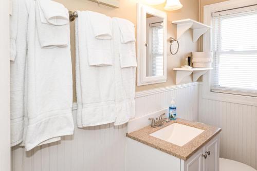 Baño con toallas blancas colgadas sobre un lavabo en Warm and Coasty - Top, en North Topsail Beach
