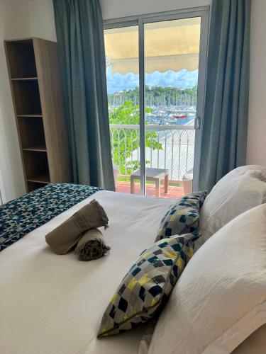 a bed with pillows and a window with a view at Marina Hill Appartement vue mer in Le Gosier