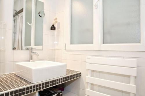 een witte badkamer met een wastafel en een spiegel bij JULES JO in Parijs