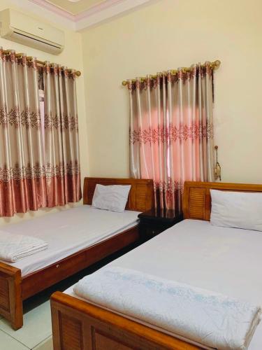 two beds in a room with curtains at Khách sạn Hoàng Trang in Cao Bằng