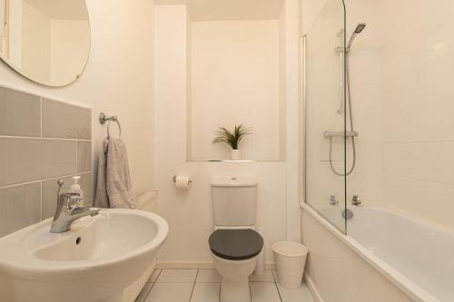 La salle de bains blanche est pourvue de toilettes et d'un lavabo. dans l'établissement Wyllie Mews, à Burton-on-Trent