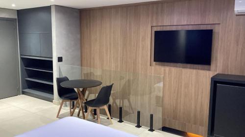 a room with a table and chairs and a television on a wall at Taikô Motel by Drops in Porto Alegre