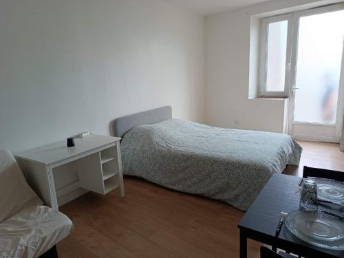une chambre blanche avec un lit et une table dans l'établissement Jolie studio, à Saint-Pourçain-sur-Sioule