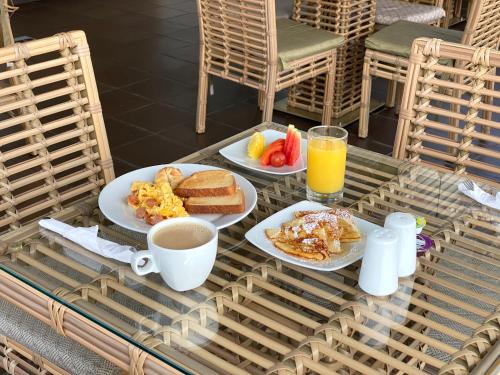 a table with two plates of breakfast foods and a cup of orange juice at Seven Inn Hotel in Medellín