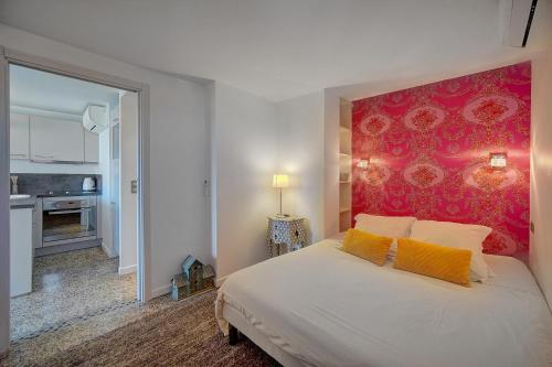 une chambre avec un grand lit avec un mur rouge dans l'établissement Le Louvre Top Floor, à Cannes