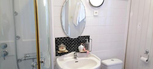 a white bathroom with a sink and a mirror at La Petite Maison des Artiste in Saint-Sulpice-les-Feuilles