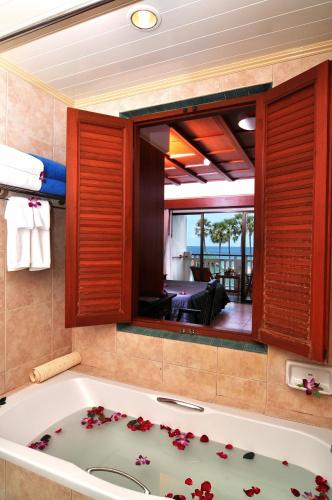 a bath tub in a bathroom with a view of a room at Karon Princess Hotel SHA EXTRA Plus in Karon Beach
