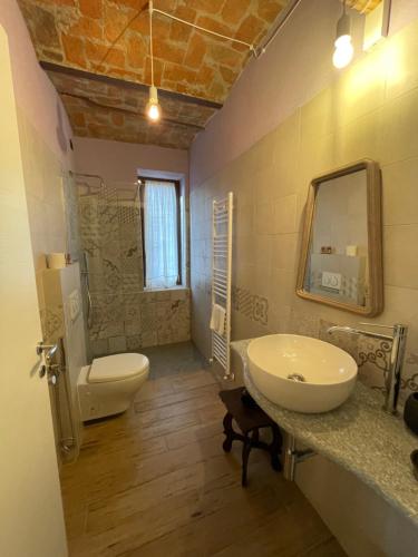 een badkamer met een wastafel, een toilet en een spiegel bij Le camere del Tiglio in Treiso